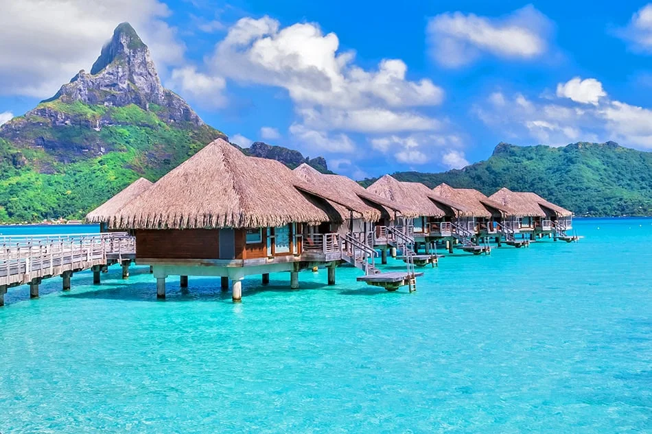 Ảnh bảo vệ môi trường với bungalow mái lá giữa làn nước biển xanh ngọc và núi rừng xanh tươi