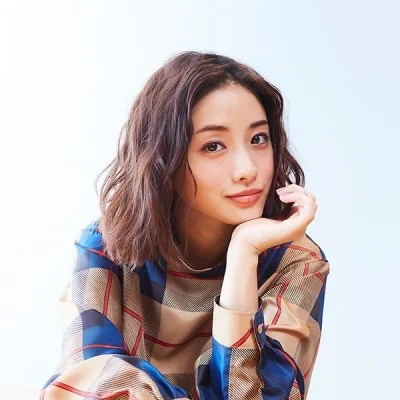 Hình ảnh cute nữ với cô gái trẻ tóc nâu gợn sóng, mặc khăn kẻ caro và tạo dáng chống cằm trên nền sáng